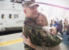 soldier hugging his wife next to military helicopter