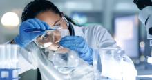 woman scientist looking closely as she pours a liquid into a beaker