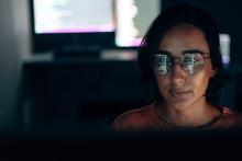 artistic photo of a computer screen reflected in a woman's glasses 
