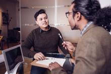 Two people talking while one of them holds a computer cord