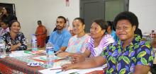 People in Fiji sitting at a table smiling during a workshop on education