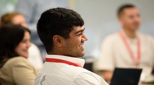 Abt Global staff smiling as they sit at a conference table in a meeting.