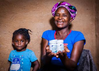 A mother holding medications with her child