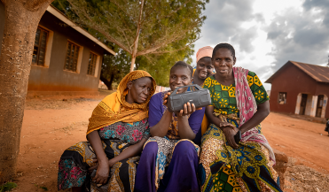 women with a handheld radio in a village in Tanzania