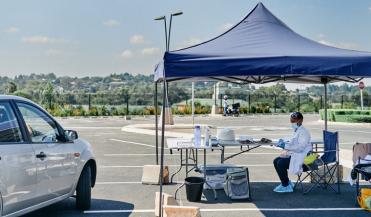 car parked next to covid testing station set up in a parking lot