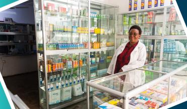 smiling pharmacist standing behind a counter in africa 