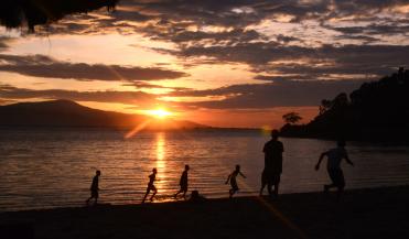 silhouette of kids running on a beach in timor leste during sunset