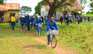 malaria control workers biking from a village in uganda