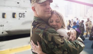 soldier hugging his wife next to military helicopter
