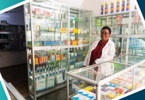 African woman pharmacist standing behind counter smiling