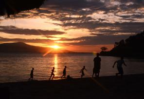 Children running on a beach in East Timor in silhouette during a setting sun