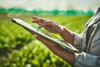woman standing among crops using digital technology