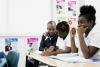 Teacher sitting next to older students in New Orleans classroom.