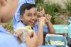 Ethnic boy eating packed lunch out side with school friends