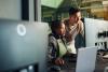 Software engineers collaborating on a project, analyzing code on computer monitors in office