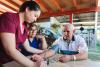 Rural medical visitor woman checking blood pressure of a senior latin male farmer patient, with a monitor