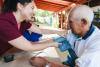 Rural medical visitor woman checking blood pressure of an elderly latin male farmer patient.