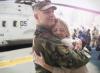 soldier hugging his wife next to military helicopter