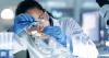 woman scientist looking closely as she pours a liquid into a beaker