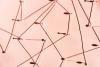 Abstract composition with strings connected by pins on a soft pastel background, forming a geometric web with sharp shadows in natural light