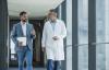 Doctor and business professional in discussion in office corridor